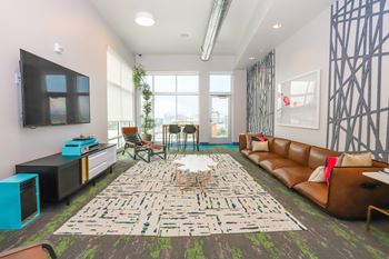 A living room with a large rug and a brown couch at RiDE at RiNo Apartments, Denver, Colorado